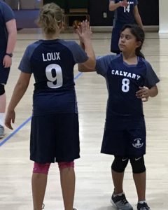 Two Calvary Christian School Girl's volleyball athletes high fiving during a match 