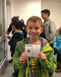 Young boy with a green coat with fingerprint card from Calvary Christian School field trip to police station