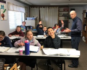 Students with their hands raised during class at Calvary Christian School